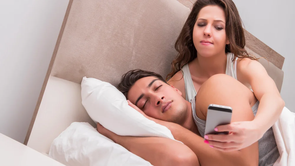 男性のスマートフォンをそっと持ち上げる女性