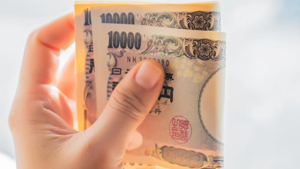 左手で1万円札を二つ折りにする