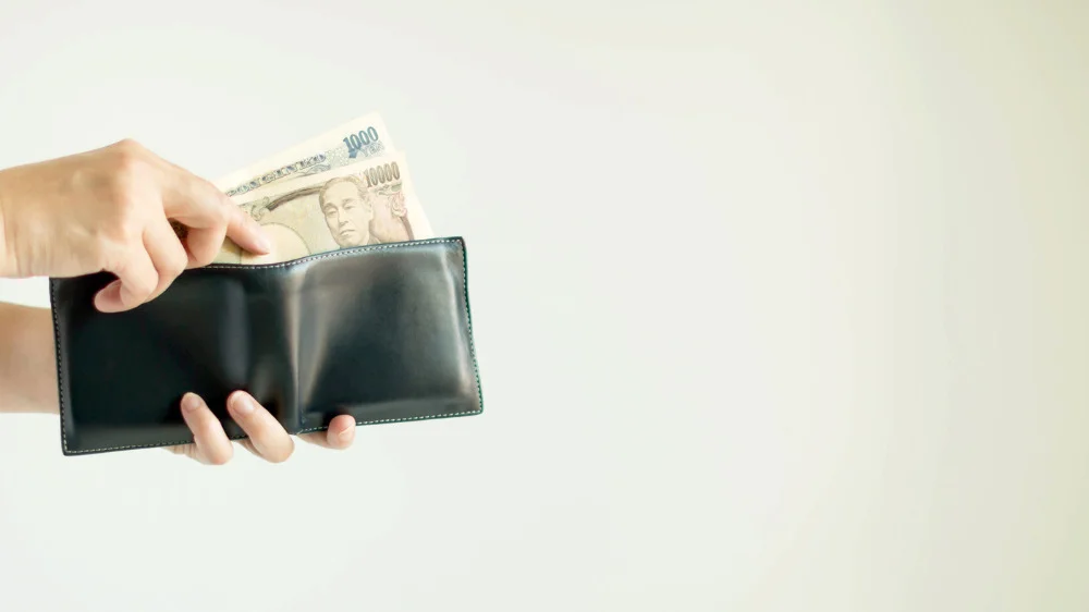 黒い財布から11,000円を右手で取り出す様子