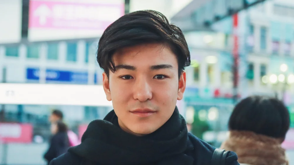 こちらを見つめる黒いマフラーを首に巻いた男性