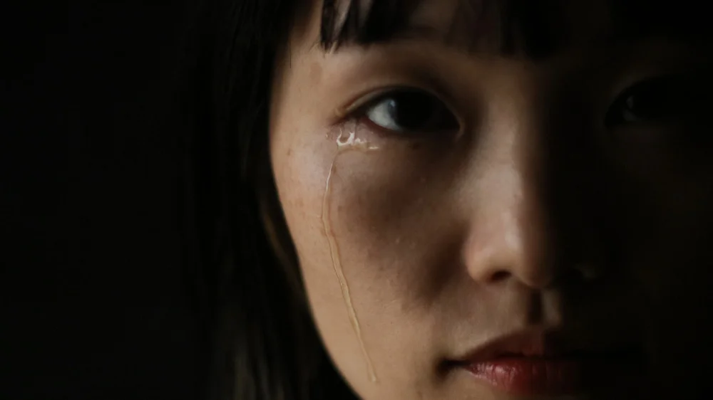 右目から涙を流しながらこちらを見る女性