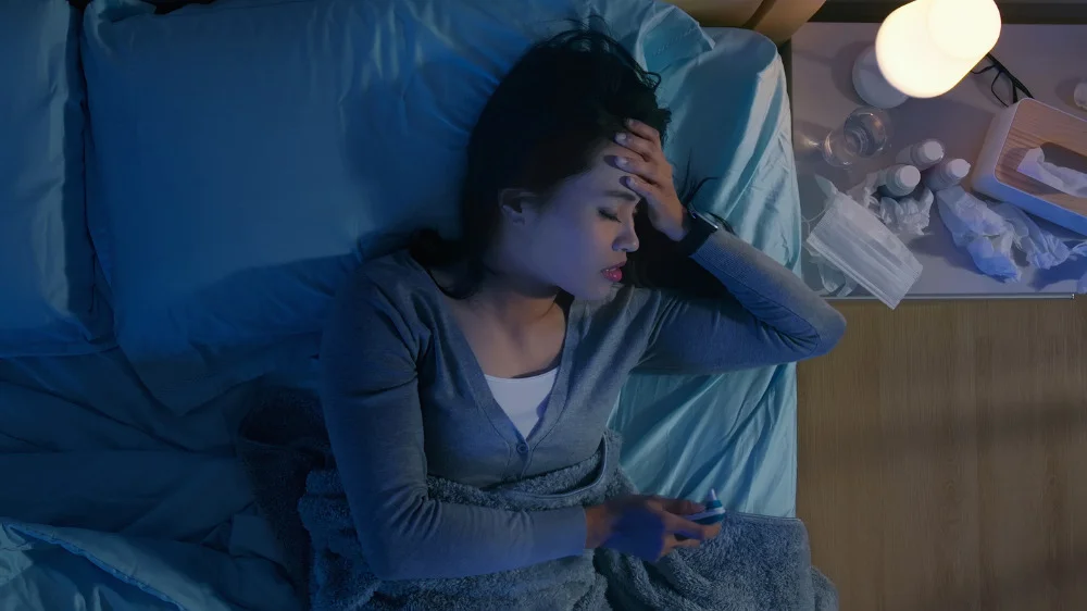 左手を自分のおでこに添えながら眠っている女性