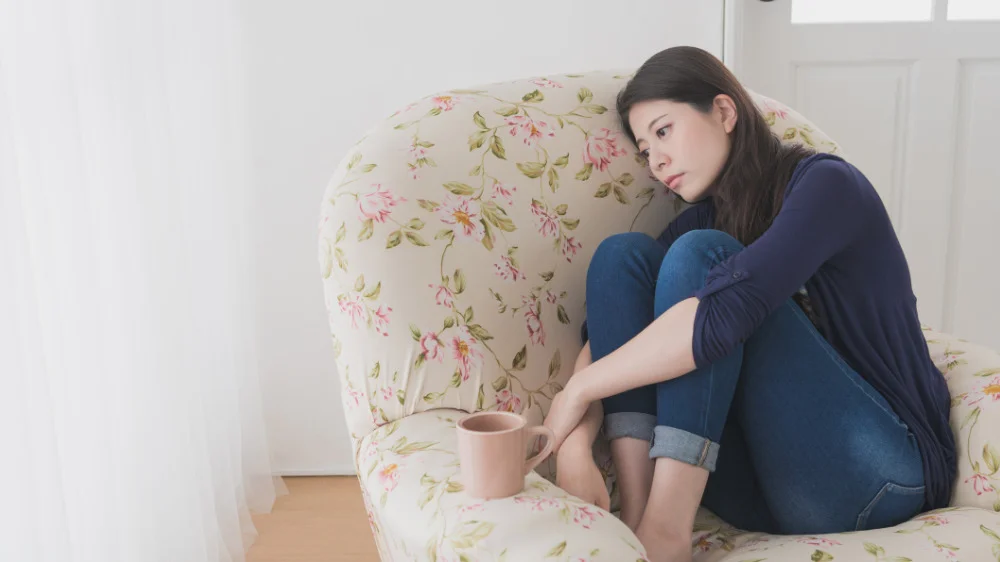 一人用ソファに横座りしながら落ち込む女性